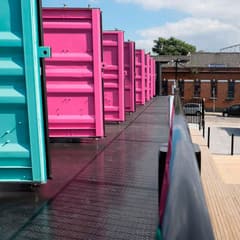 Pink and teal shipping container units at Containerville