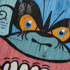 Graffiti monster face painted on wooden doors in Hackney
